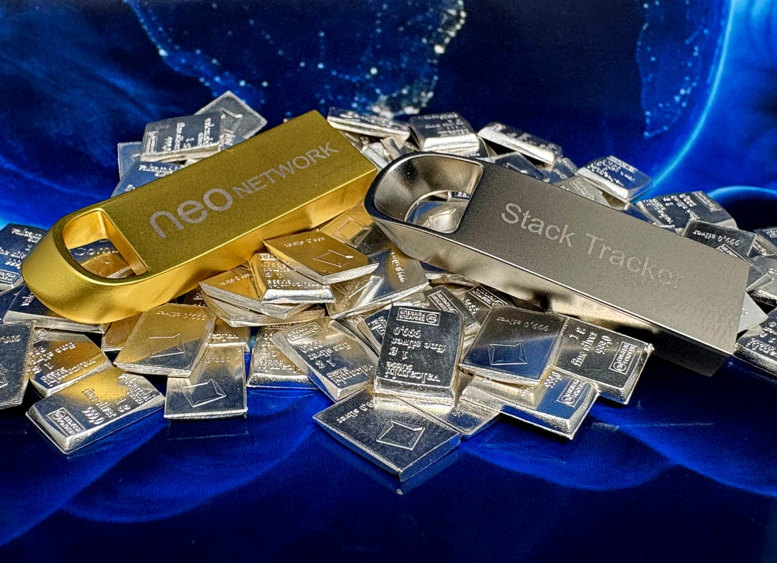 Gold Neo Network and silver Stack Tracker USB editions displayed with silver bars